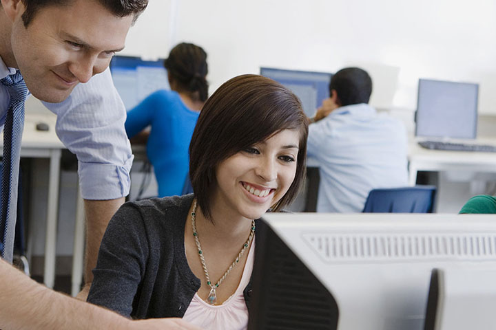 Smiling girl student looking at bibliography vs works cited on a computer with her teacher